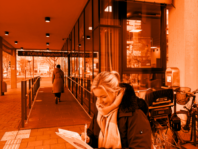 Foto von einer Person, die vor der VHS mit einem Fragebogen steht